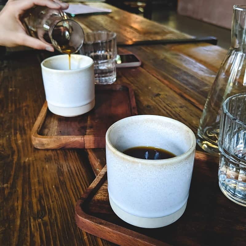 Filter coffee poured into a pale ceramic tumbler on a wooden bar