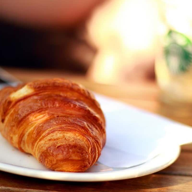A golden butter croissant on a white plate