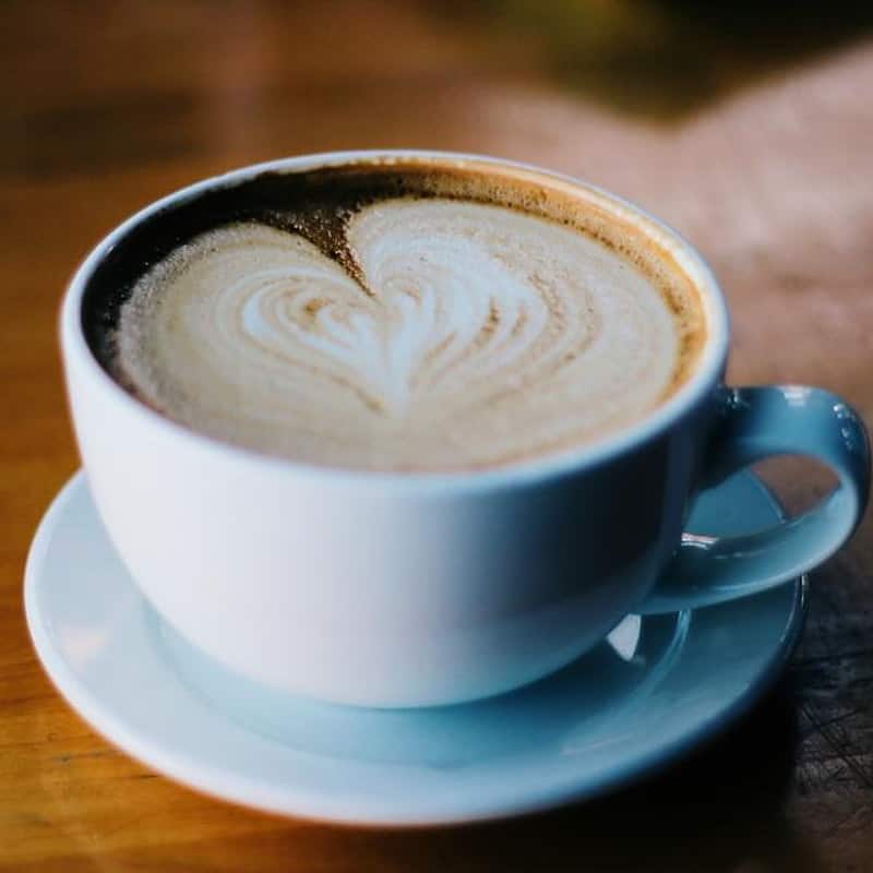 A cappuccino with a heart poured into the foam, in a white cup on a blue saucer