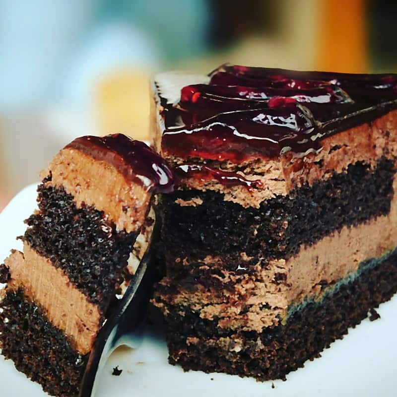 Slices of layered chocolate cake finished with a dark cherry glaze
