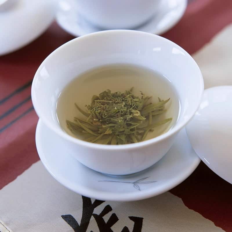 Sencha leaves steeping in a white porcelain cup