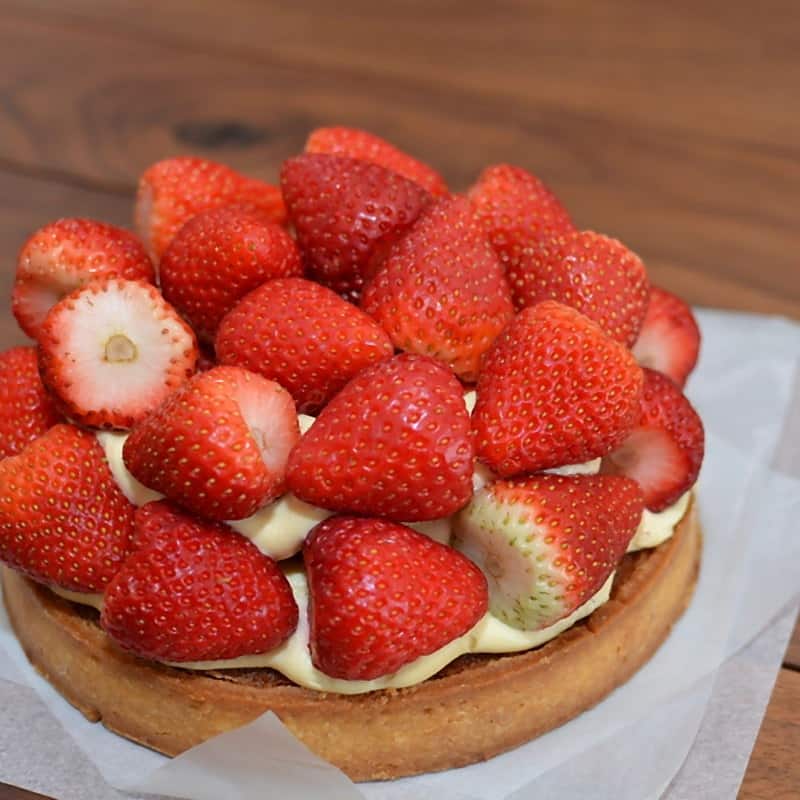 A strawberry tartlet packed with halved berries over crème pâtissière
