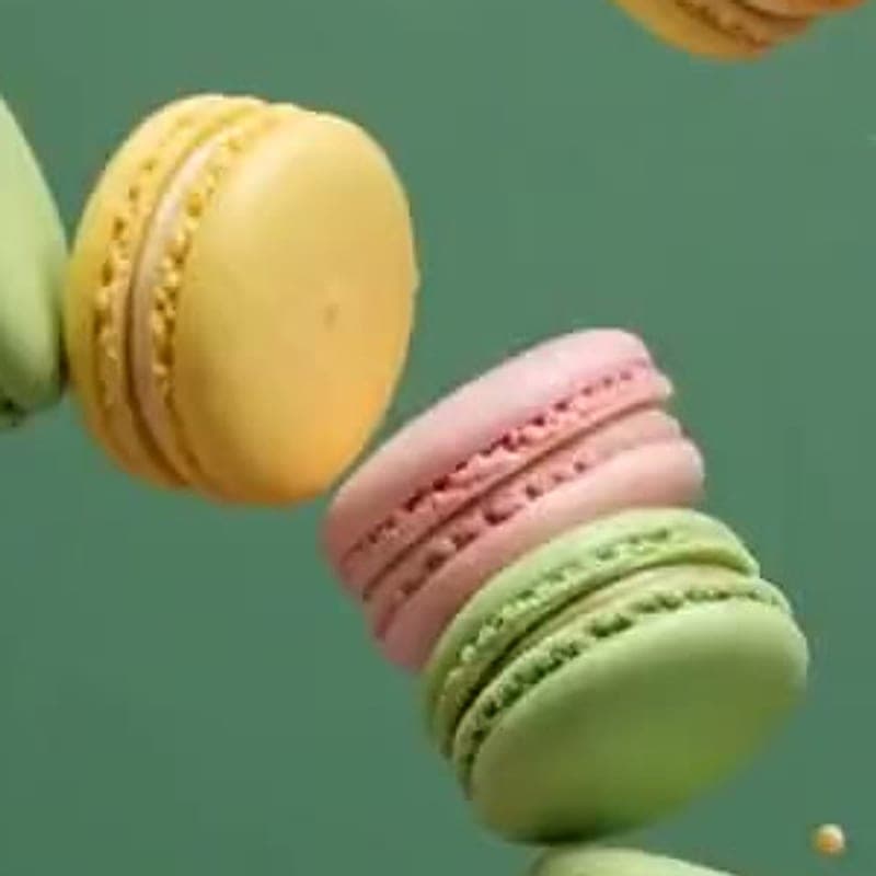 Pale yellow vanilla macaron on a green backdrop