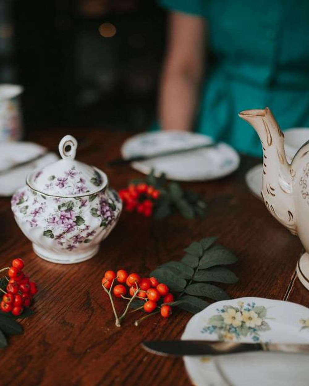 A floral porcelain tea service laid out on a wooden table